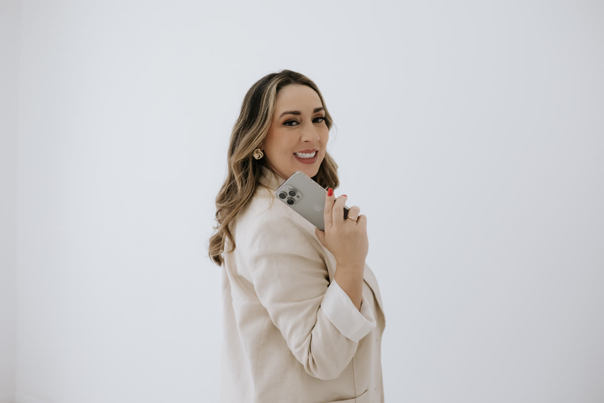 Edkarla Almeida de perfil, sorrindo, com o celular apoiado no ombro